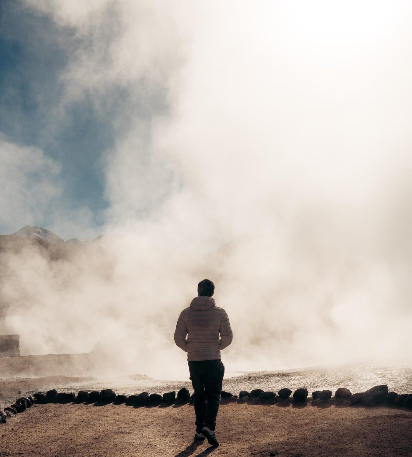 A traveller walking among the fumaroles of the El Tatio geysers at dawn