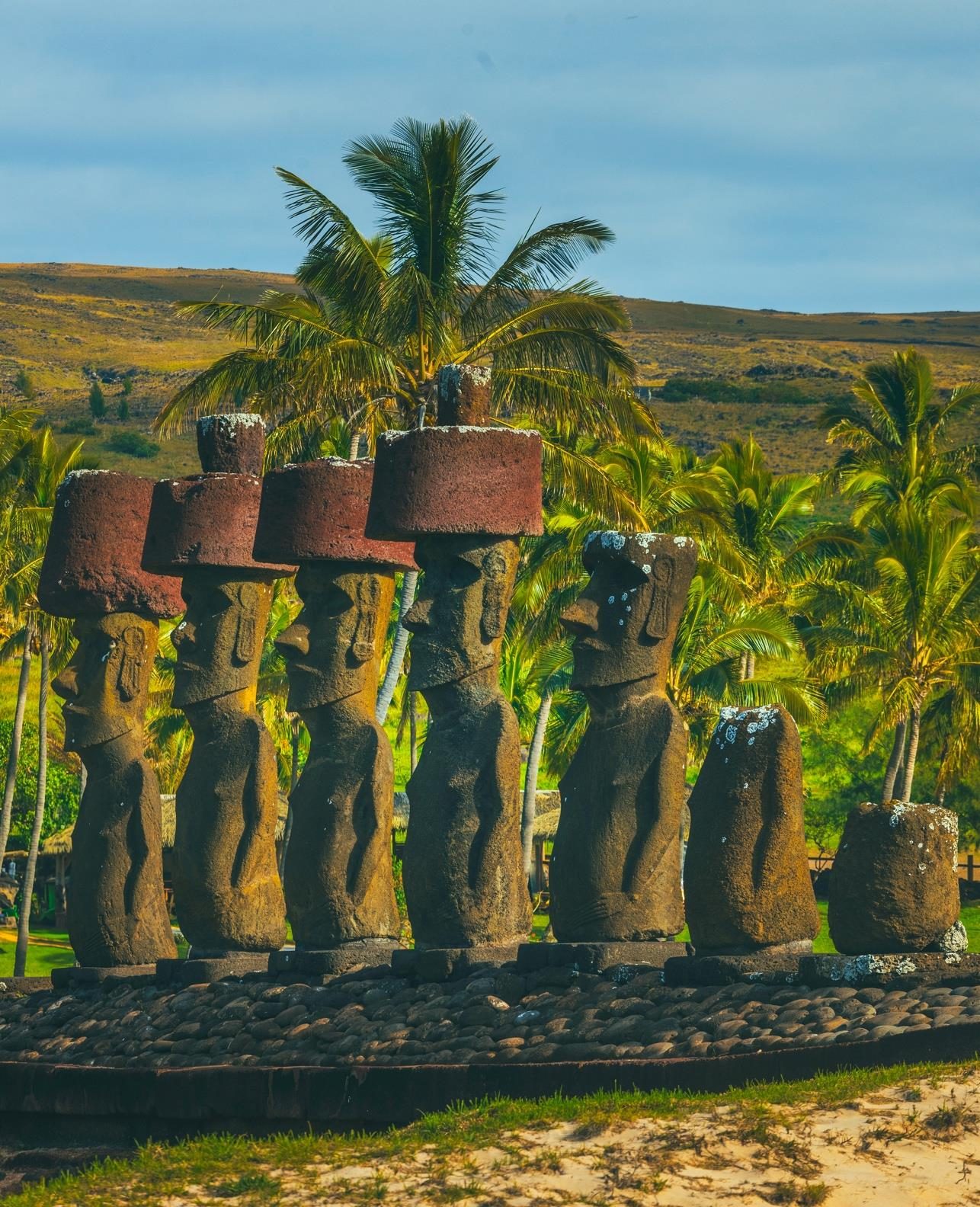 Moai with red pukao on Anakena beach, among palm trees