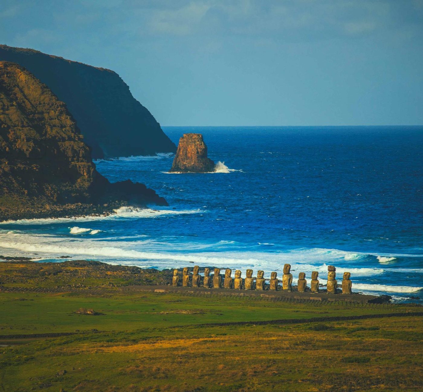 The coast of Rapa Nui with a row of moai facing the ocean and green cliffs